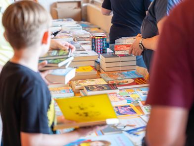 Ein Kind stöbert durch einen Tisch mit Büchern