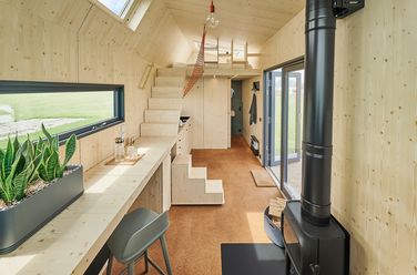 Hochebene mit Treppe, Ofen und Tisch im Green Tiny House