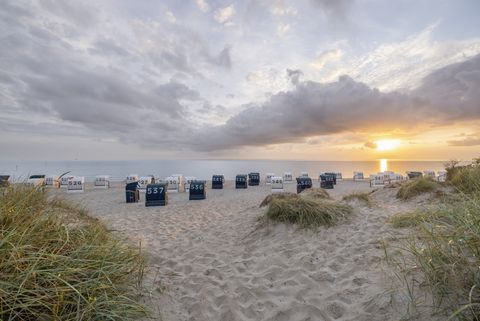 Strand bei Sonnenuntergang mit Strandkörben und Dünen im Vordergrund