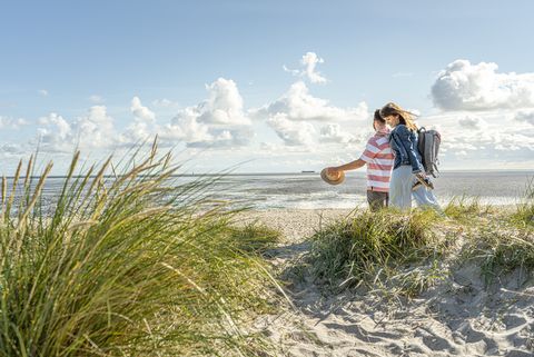 Ein Pärchen spaziert durch die Dünen zum Strand