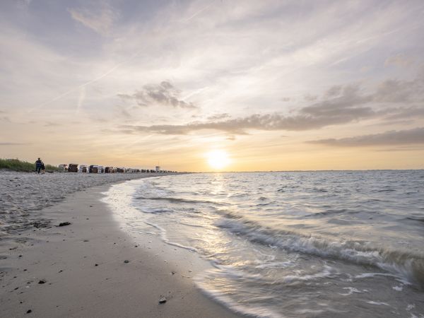 Sonnenuntergang am Strand mit Wasserkante im Vordergrund