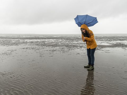 Frau mit umgeklappten Regenschirm im Watt