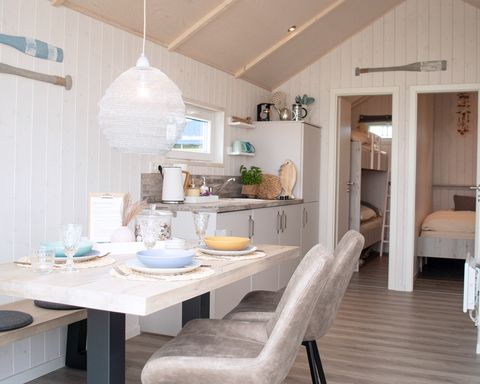 Kleines, gemütlich eingerichtetes Ferienhaus mit gedecktem Tisch im Vordergrund