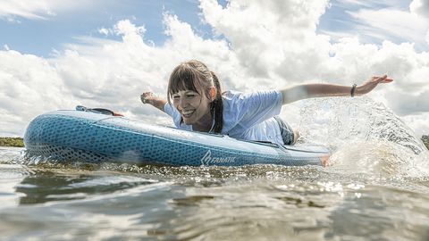 Frau liegt auf Surfbrett und paddelt