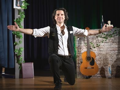 Schauspieler Vasilios Zavrakis mit ausgebreiteten Armen auf der Bühne 