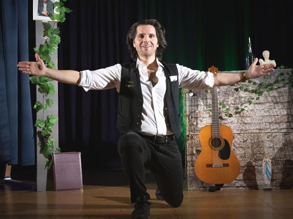 Schauspieler Vasilios Zavrakis mit ausgebreiteten Armen auf der Bühne 