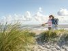 Ein Pärchen läuft durch Dünen zum Strand