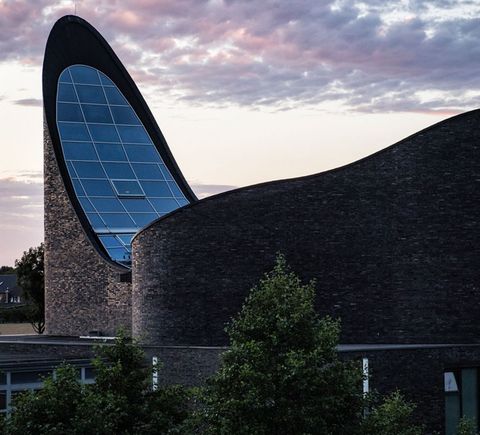 Kirche mit gläsernen Dach in Wellenform im Abendlicht