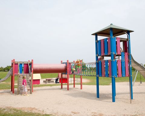 Spielplatz mit Kletterturm und Rutsche auf einer Sandfläche