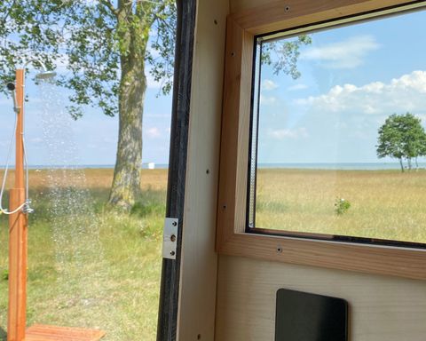 Blick aus der Strandkorbsauna auf die laufende Outdoor-Dusche
