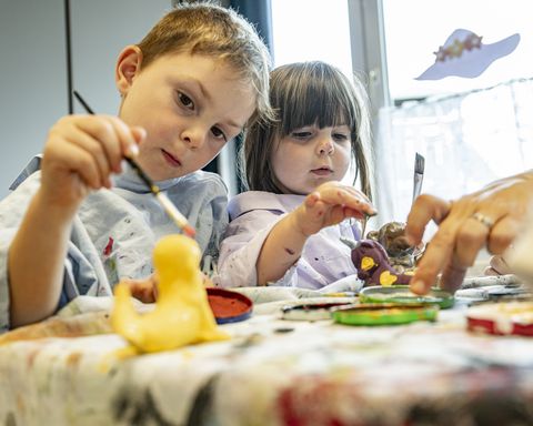 Zwei Kinder bemalen Keramikfiguren 