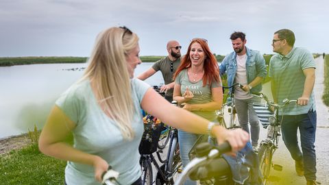 Eine Gruppe aus 5 Personen, die sich unterhält, während sie ihre Fahrräder schieben.